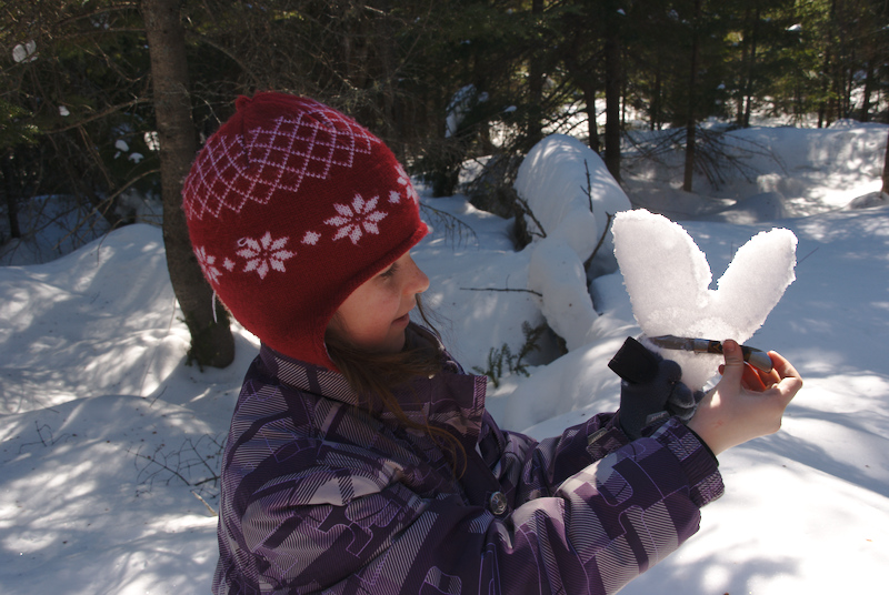 Emma s'amuse à découper des formes dans la neige...